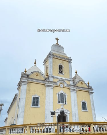 Igreja matriz de Resende Costa com fachada amarela e branca sob céu nublado em Minas Gerais