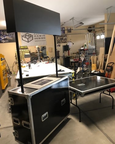Custom black flight case trade show booth with signage and portable folding table in a workshop.