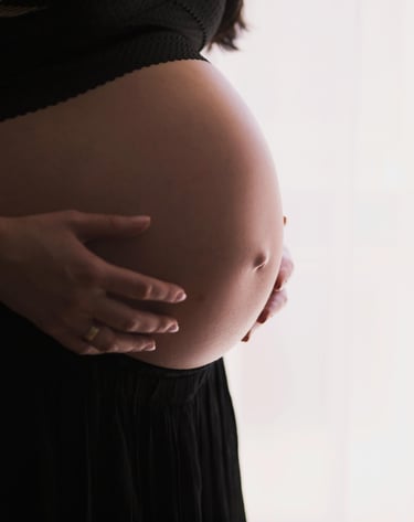 a bare pregnant belly of a woman wearing black pants