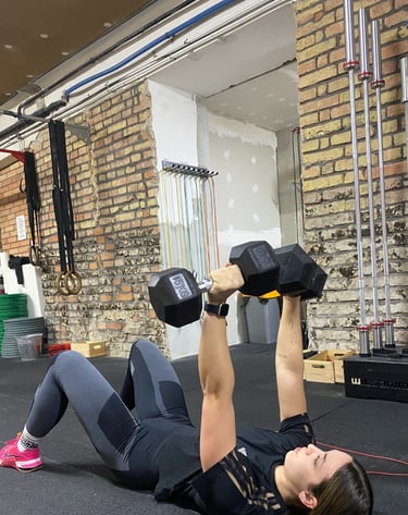 egy nő push press-t végez dumbell-ekkel