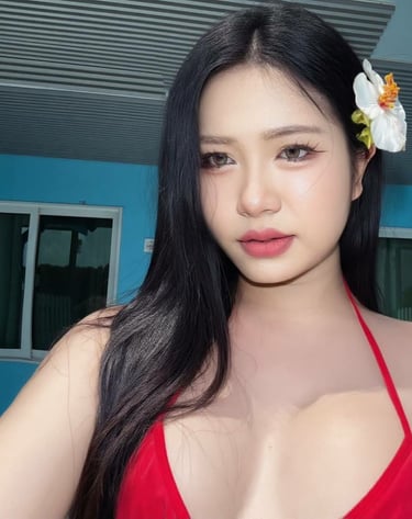 Ladyboy with flower in her hair and wearing a low cut red top