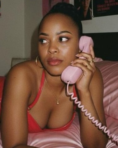 Lady lying on bed with a red dress with an ols analogue phone to her ear