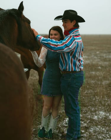 a man and woman standing in a field with horses