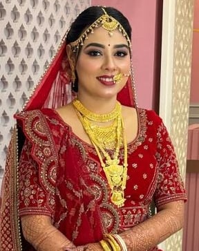Indian bride in traditional red lehenga with HD bridal makeup, multi-layered gold jewelry, mehendi, 