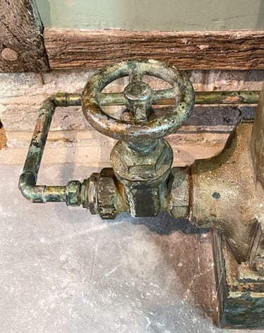 Close-up on a painted radiator valve and a painted copper pipe on antique plaster wall