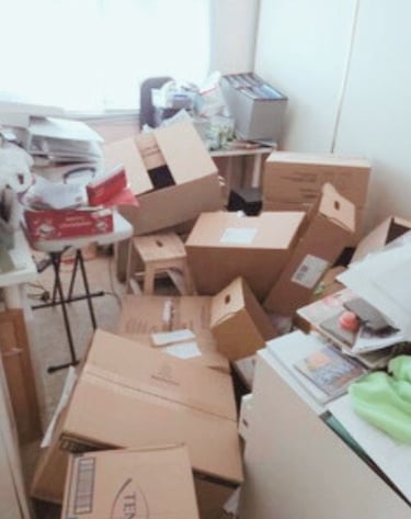 Cluttered sewing room with boxes and paperwork, needing organisation.