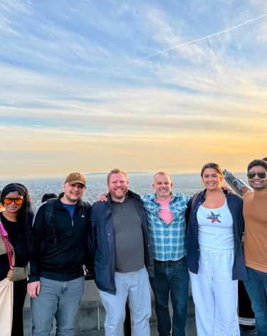 Diverse group of friends posing at Griffith Observatory during a vibrant Los Angeles sunset.