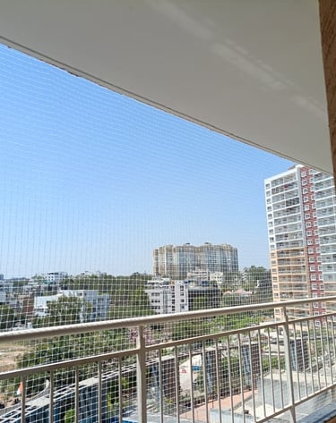 Wide shot of a multi-story apartment building in Whitefield with safety nets installed on balconies.