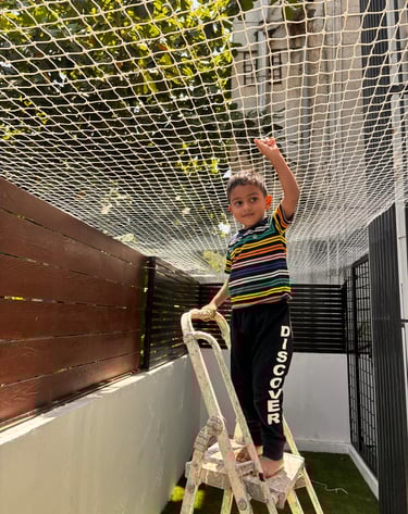 Technician from Arjilli Enterprises installing pigeon nets carefully on a residential balcony