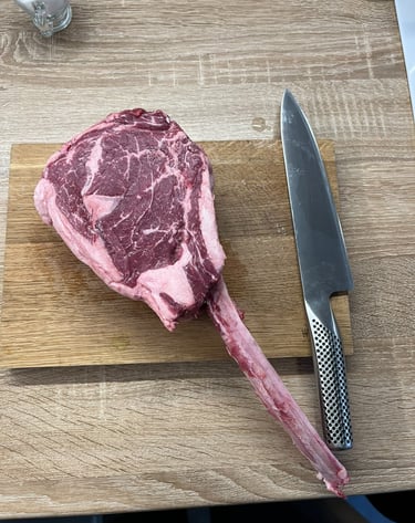 Surowy stek tomahawk i nóż na desce. Ubezpieczenia A&K Wawro to też miłość do gotowania.