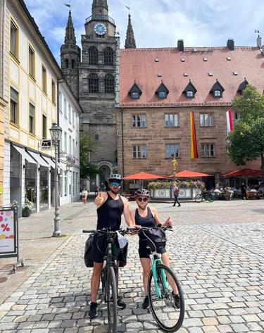 Karolina i Arek na rowerach na rynku zabytkowego miasta. Twój doradca ubezpieczeniowy w akcji.