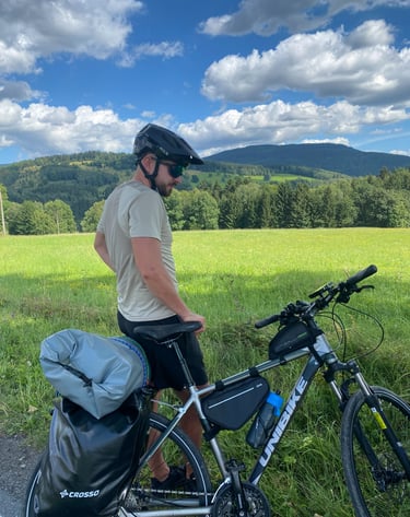 Arek z rowerem na tle zielonych łąk i gór. Ubezpieczenia A&K Wawro to też pasja do sportu.