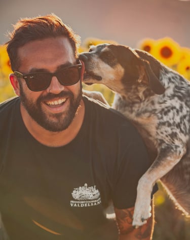 un cane meticcio con macchie nere bacia il padrone, un ragazzo con gli occhiali da sole