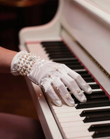 A close-up, artistic photograph of a hand in an elegant evening glove resting on a pearl white piano, set in a dimly lit North American / US jazz club with warm, muted rose highlights.