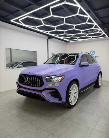 Matte purple Mercedes-Benz SUV with white wheels under hexagonal LED garage lighting.