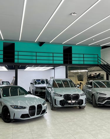Luxury sports cars including a BMW M3 and Lamborghini Urus in a modern automotive detailing garage.