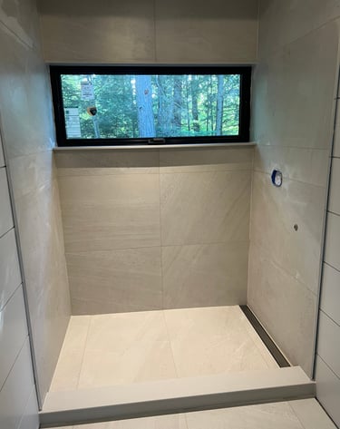 Modern walk-in shower featuring large beige porcelain tiles.