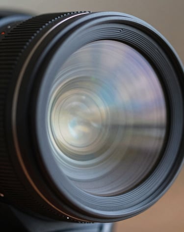A close-up photograph of a professional camera lens reflecting a Soft Blue and Pale Grey sky, emphasizing technical precision and elegance.