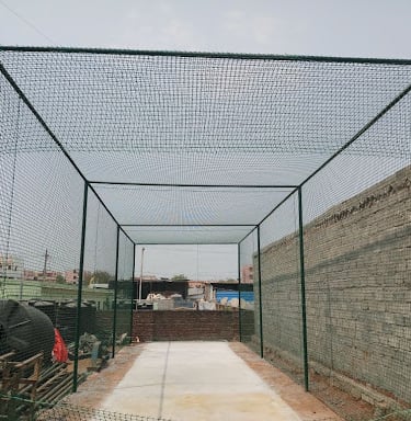 Technician carefully fitting safety nets around a terrace sports area in a busy Mumbai neighborhood.