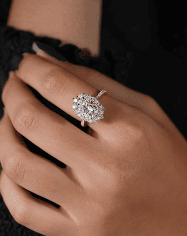 Elegante anillo de diamantes con halo ovalado en oro rosa, lucido en la mano de una mujer