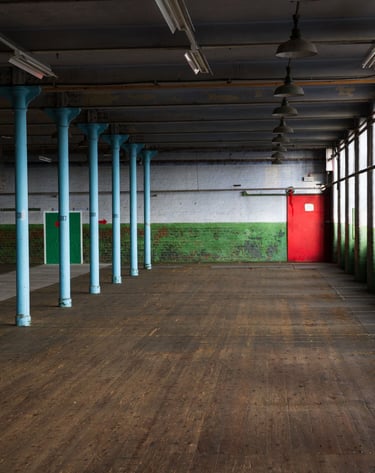 The Main room at Atlas Studios, with original wooden flooring peeling paint on the walls and original cast iron sliding door