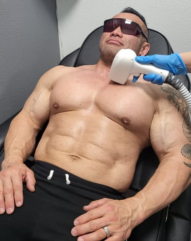 Muscular man receiving professional laser hair removal treatment on his chest at a medical spa.