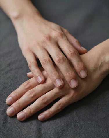 Close-up detail shot of two hands holding, one resting on a charcoal-colored fabric. The lighting is soft and warm, highlighting the natural textures. Cinematic and emotional style, focusing on the connection.