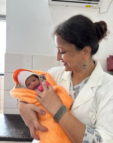 Dr. Rrenu Agraeal, Rini Hospital Dholpur-a woman in a white coat holding a baby in a hospital