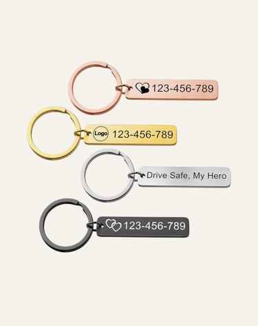 Custom engraved metal bar keychains in rose gold, gold, silver, and black with personalized phone numbers.