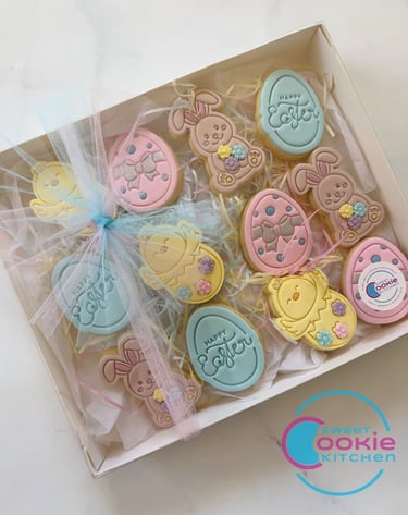 A box of colorful Easter-themed sugar cookies, featuring bunnies, chicks, and eggs with "Happy Easter" greetings, perfect