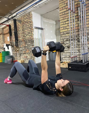 egy nő push press-t végez dumbell-ekkel