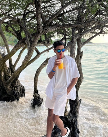 Male massage therapist leaning against a tree by the beach