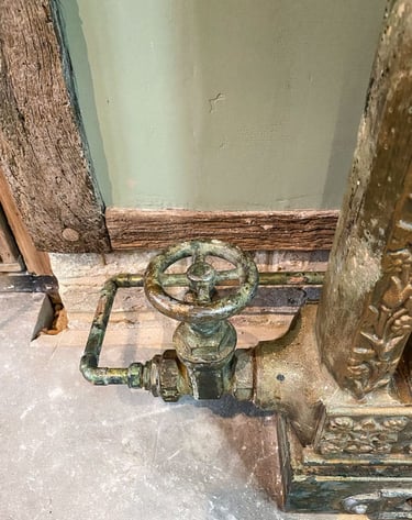Close-up on a painted radiator valve and a painted copper pipe on antique plaster wall