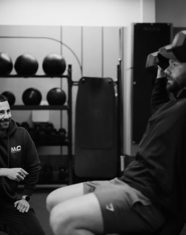 Trainer observing client’s seated dumbbell shoulder press in Leamington Spa gym, highlighting coaching and strength training.