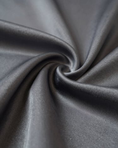 Macro photography of draped silk fabric in deep shadow, with subtle highlights in #B5A591 catching the texture, creating a premium and artistic visual experience.