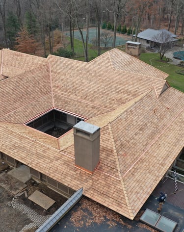 Aerial view of a luxury home featuring a new cedar shake roof with copper flashing and gutters.
