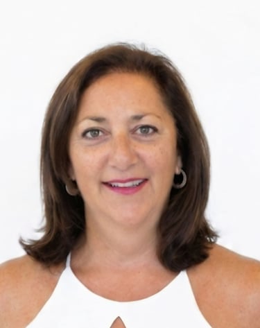 Professional headshot of a smiling woman with brown hair in a white top against a plain background.