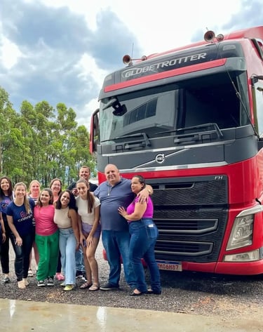 Equipe da Caran Contabilidade junto aos parceiros da Xandão ao lado de caminhão vermelho.