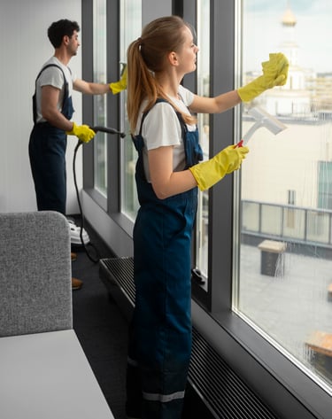 a woman and a man cleaning a window with a vacuum