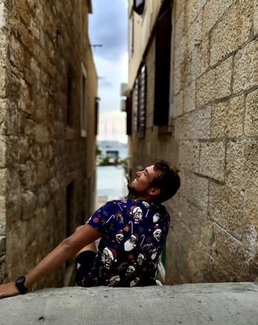 Man smiling while sitting in narrow street of Komiza town on the island of Vis, during a private boat tour from Split Croatia