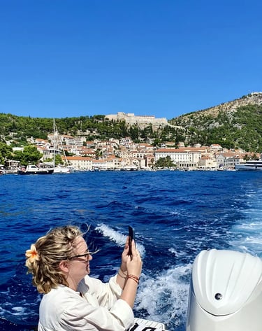 Woman photographing the coastline of Hvar, Croatia and Fortica fortress from a boat on a private tour from Split