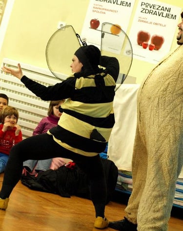 Actors in bee and bear costumes performing a children's play for an attentive audience.