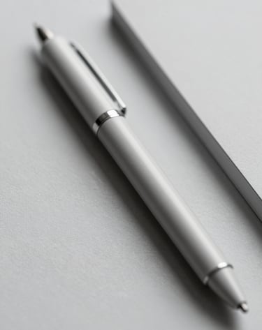A macro shot of high-quality, textured stationery in light gray (#D8D8D8). A single pen rests beside it. The depth of field is shallow, highlighting the tactile quality of the materials. Minimalist lighting and a calm, quiet mood.