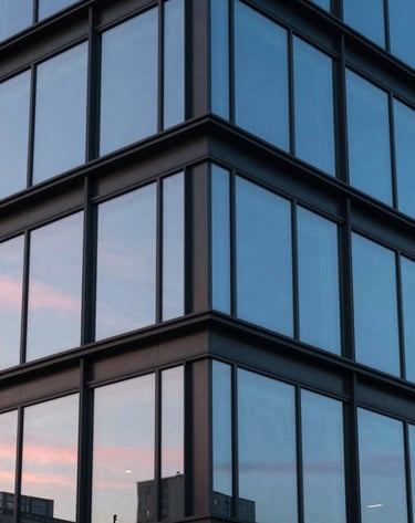 Detailed close-up of a modern North American / US architectural facade, highlighting the intersection of glass and steel. Sophisticated composition with a cool cerulean blue sky reflected in the windows and soft pink sunset light.