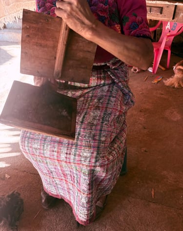 Una tejedora guatemalteca que utiliza herramientas tradicionales de cardado de lana de madera 