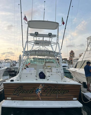 A luxury sport fishing boat docked in a marina featuring a wooden transom with custom typography.