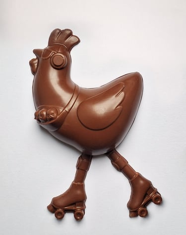 Milk chocolate Easter chicken wearing sunglasses and roller skates on a plain white background.