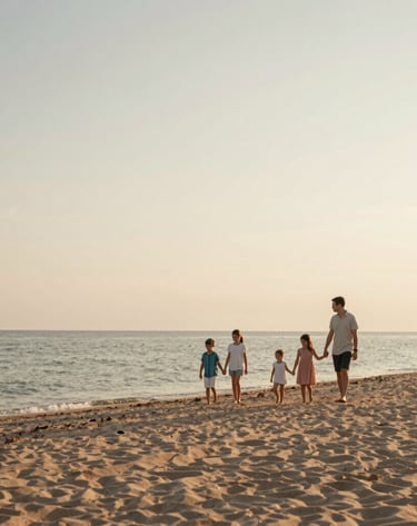 A wide-angle photography shot of a family walking hand-in-hand along the sandy shore of Lake Michigan. The sky is a soft blend of Cream and Soft Brown. The overall mood is sophisticated, light, and airy, reflecting a warm summer evening.
