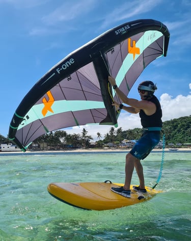 a man is holding a wing on a beginner foil board in the water, in a crystal clear lagoon