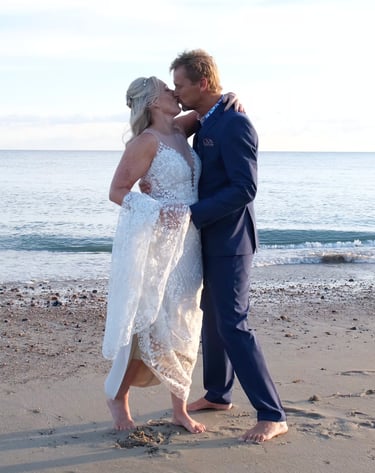 A bride and groom dance on a sandy beach 